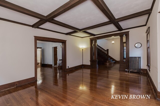 empty room with radiator heating unit, wood finished floors, coffered ceiling, and decorative columns