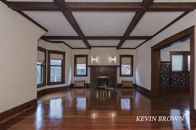 unfurnished living room featuring a brick fireplace, radiator, wood finished floors, and coffered ceiling