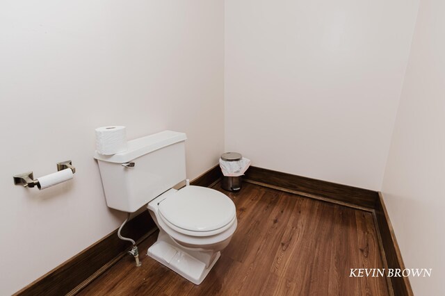 bathroom with toilet, wood finished floors, and baseboards