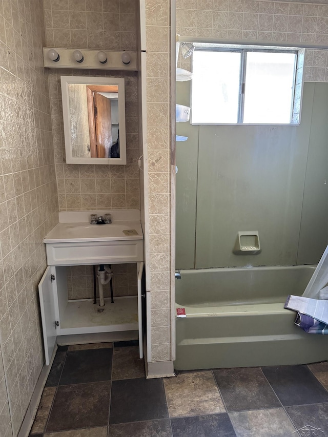 bathroom with bathing tub / shower combination and tile walls