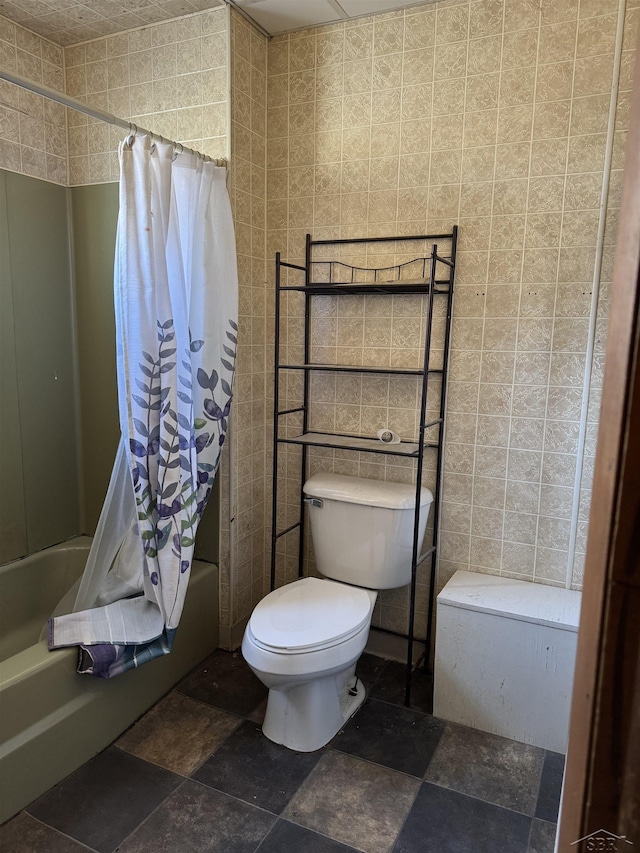 bathroom featuring toilet, shower / bath combo with shower curtain, and tile walls