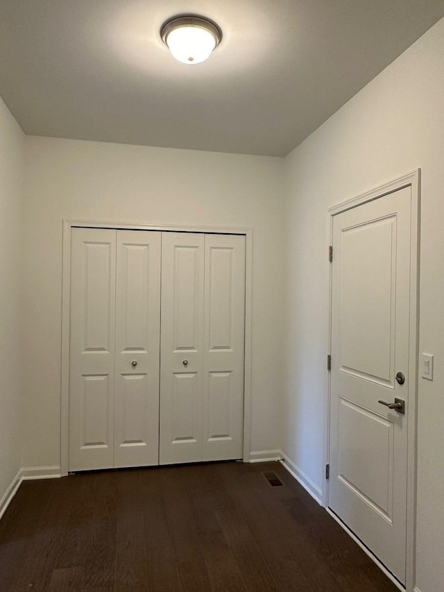 unfurnished bedroom featuring dark wood-type flooring and a closet