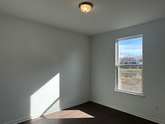 spare room with plenty of natural light and dark hardwood / wood-style floors