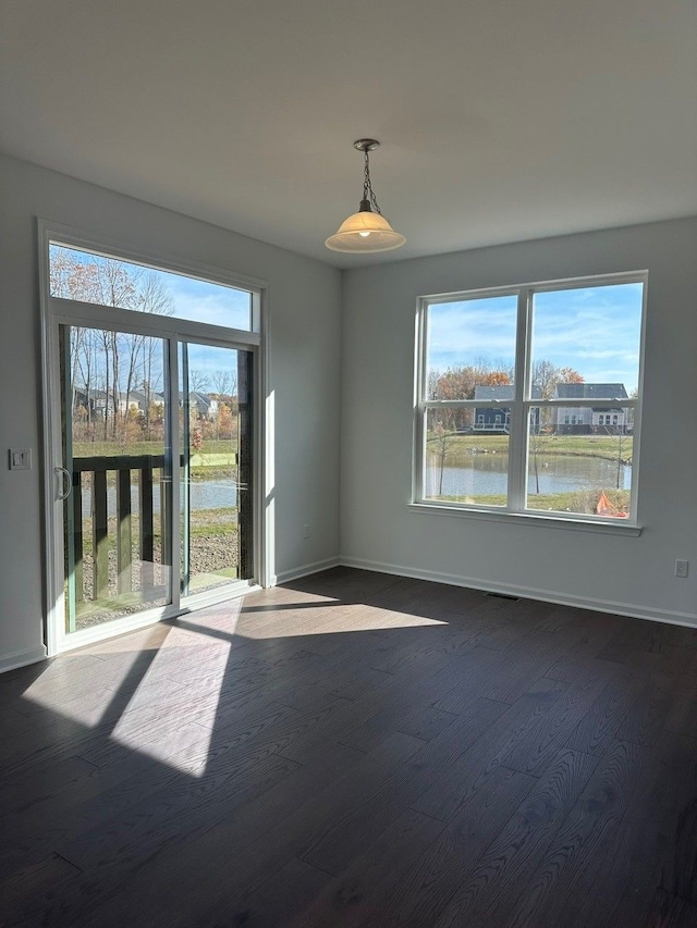 empty room with hardwood / wood-style floors and a water view