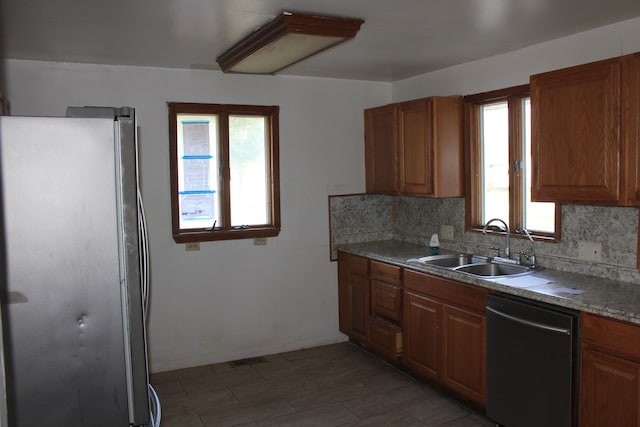 kitchen featuring stainless steel fridge, black dishwasher, plenty of natural light, and sink