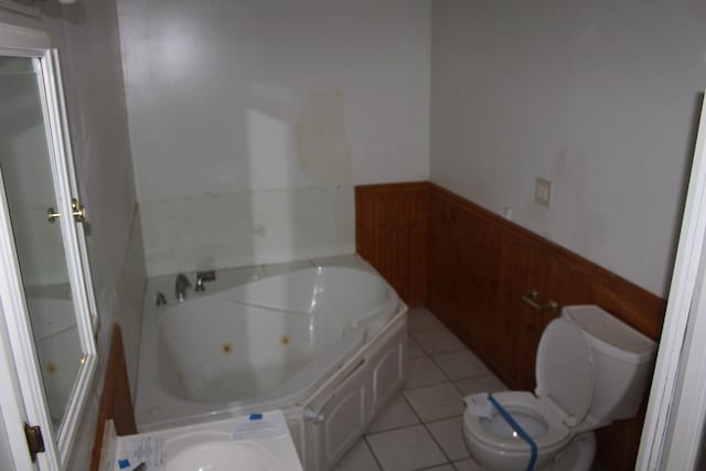 bathroom featuring a tub, wood walls, tile patterned flooring, and toilet