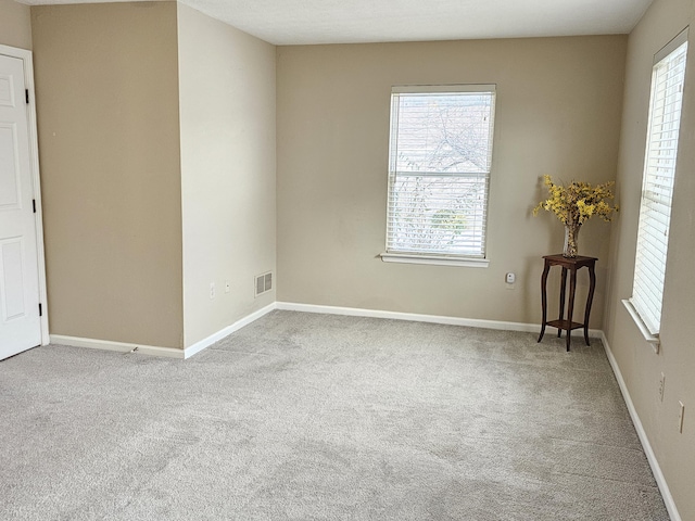 spare room with light carpet and plenty of natural light