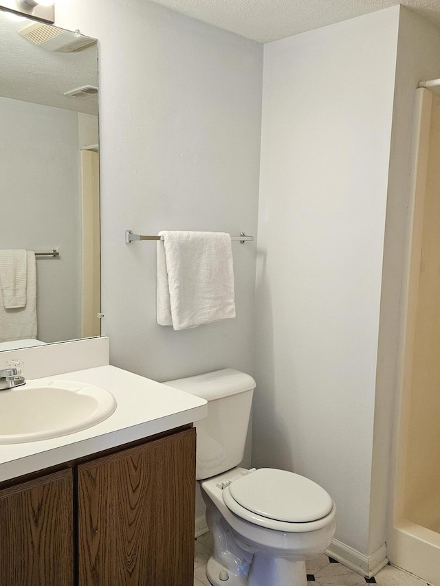 bathroom featuring tile patterned flooring, a textured ceiling, vanity, and toilet