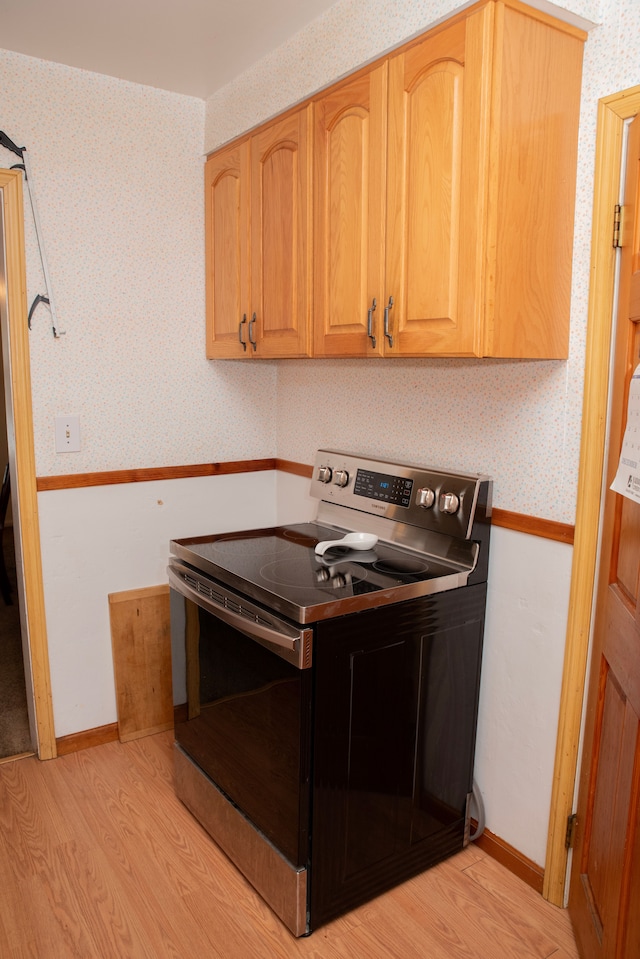 kitchen with electric range and light hardwood / wood-style flooring