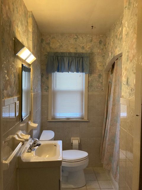 bathroom with vanity, tile walls, tile patterned flooring, toilet, and curtained shower