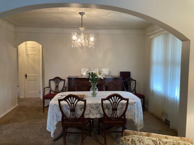 carpeted dining area with a notable chandelier