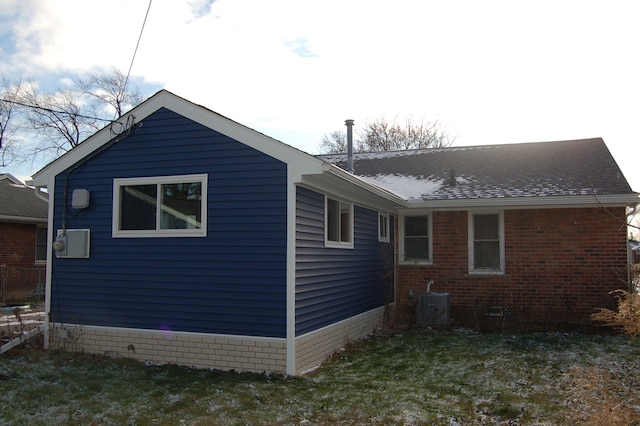 view of home's exterior with central air condition unit, a yard, a shingled roof, and brick siding