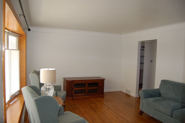 living area with wood finished floors, visible vents, and baseboards