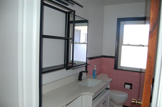 half bath featuring wainscoting, tile walls, toilet, and vanity