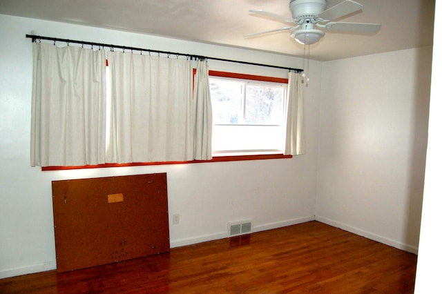 spare room with baseboards, visible vents, ceiling fan, and wood finished floors