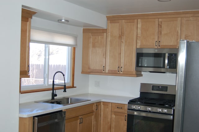 kitchen featuring stainless steel appliances, a sink, and light countertops