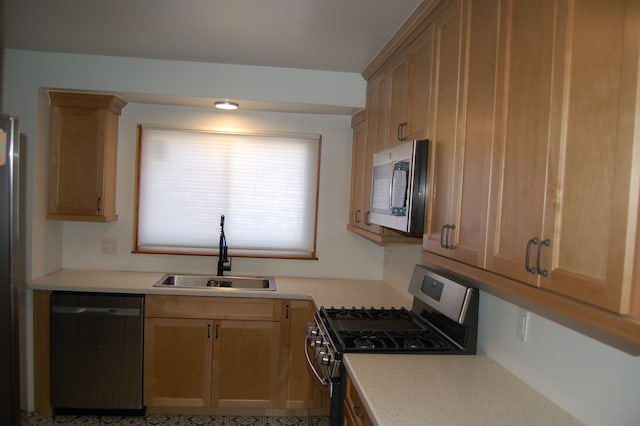 kitchen with light brown cabinetry, stainless steel appliances, a sink, and light countertops