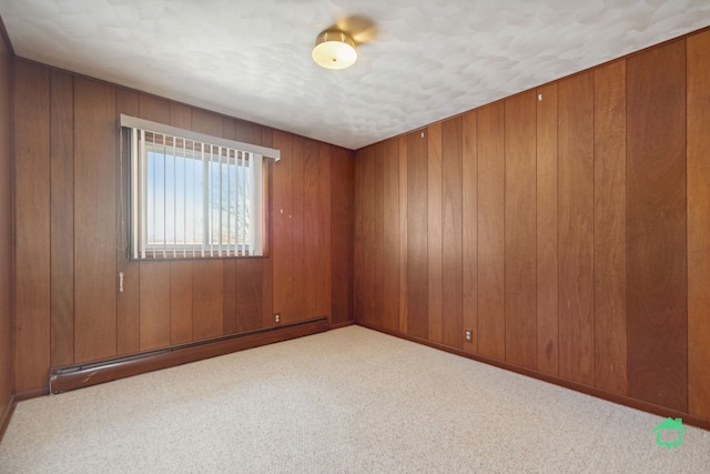 spare room featuring light carpet, a baseboard radiator, and wood walls