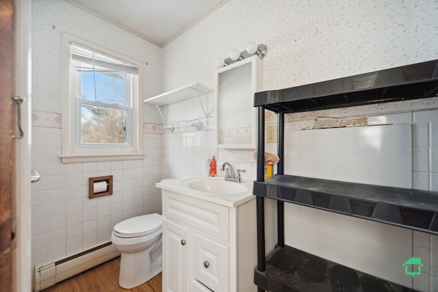 bathroom featuring baseboard heating, crown molding, hardwood / wood-style floors, and tile walls