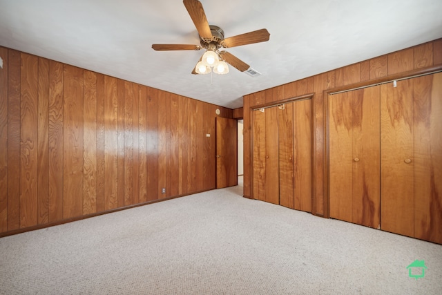 carpeted spare room with ceiling fan and wood walls