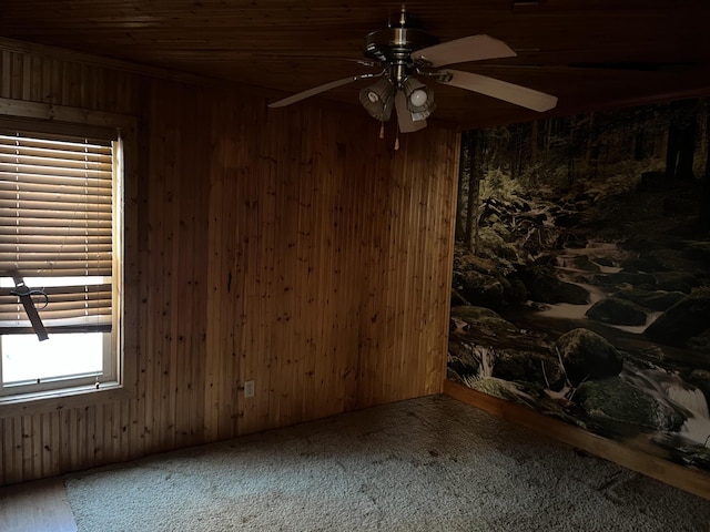 carpeted empty room with wood ceiling, ceiling fan, and wooden walls