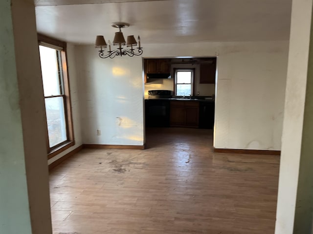 unfurnished dining area featuring sink, a notable chandelier, and light wood-type flooring