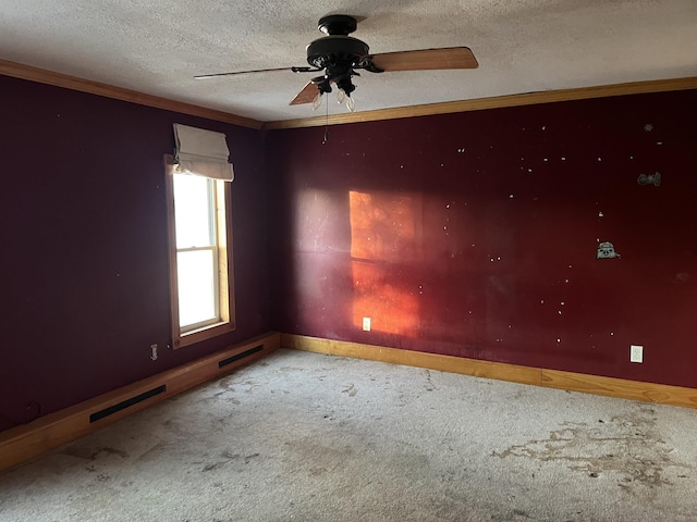 empty room with crown molding, ceiling fan, carpet flooring, and a textured ceiling