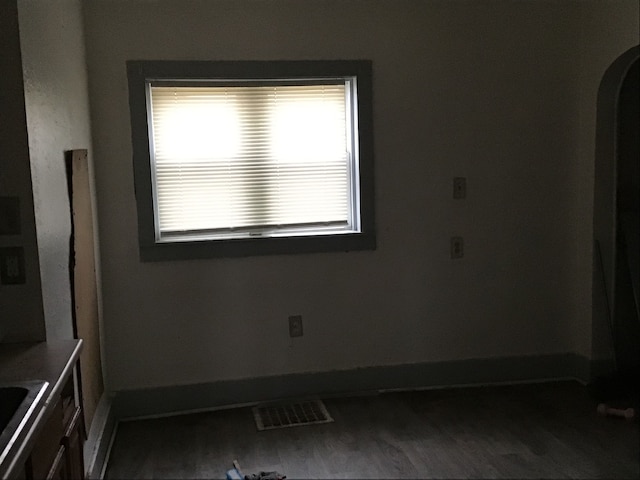 spare room featuring baseboards, visible vents, arched walkways, wood finished floors, and a sink