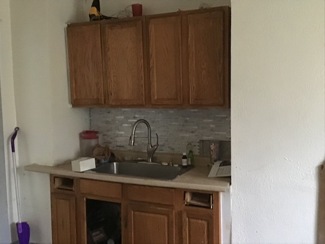 kitchen featuring light countertops, brown cabinetry, and a sink