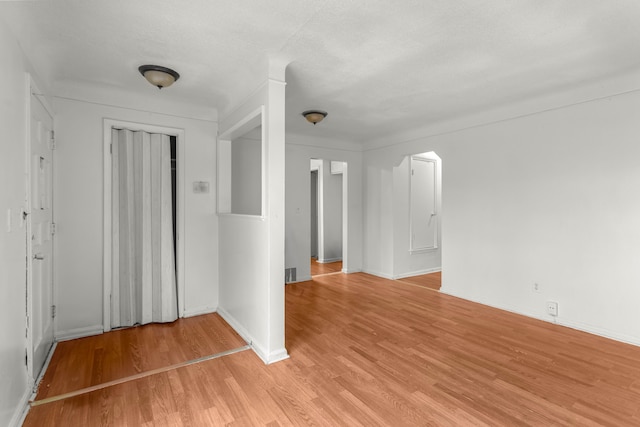 empty room with light wood-type flooring and a textured ceiling