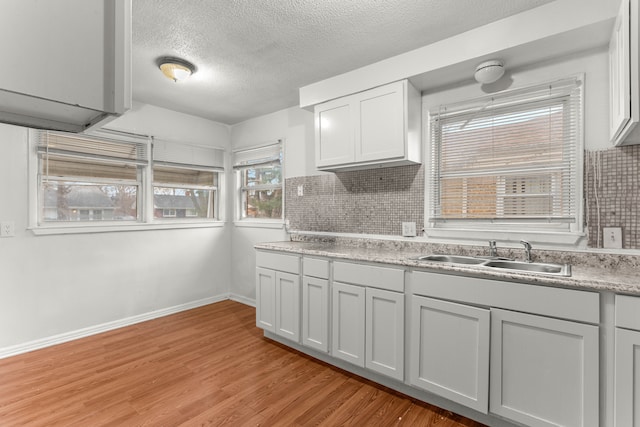 kitchen featuring a textured ceiling, backsplash, light hardwood / wood-style floors, and sink