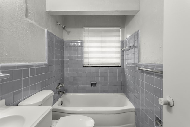 full bathroom featuring vanity, tiled shower / bath combo, tile walls, and toilet