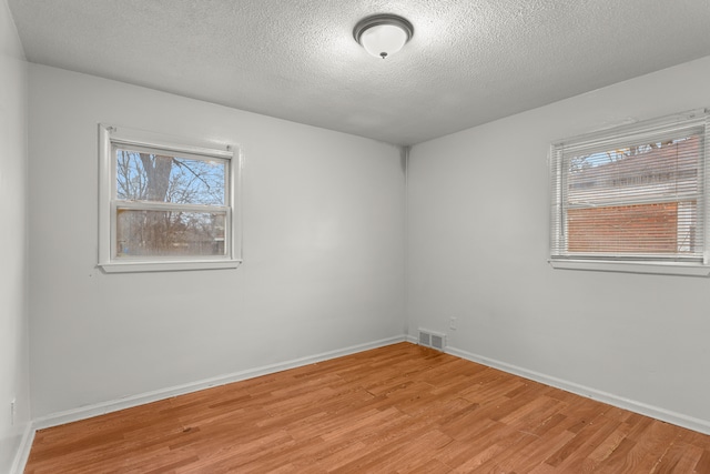 spare room with a textured ceiling and light hardwood / wood-style flooring