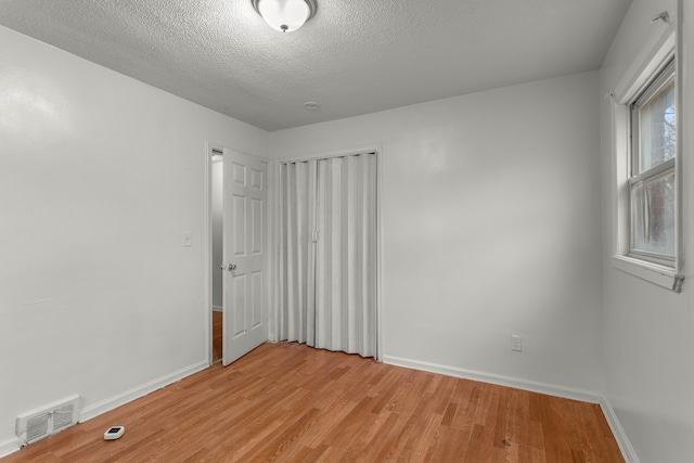 unfurnished room featuring light wood-type flooring and a textured ceiling