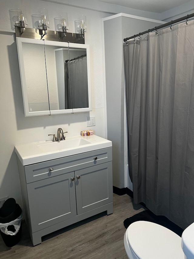 bathroom featuring wood-type flooring, vanity, toilet, and curtained shower