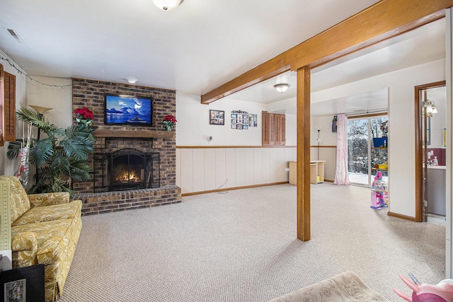 carpeted living room with a fireplace and beamed ceiling