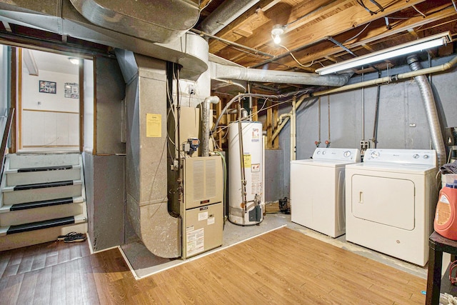 basement featuring hardwood / wood-style flooring, gas water heater, separate washer and dryer, and heating unit