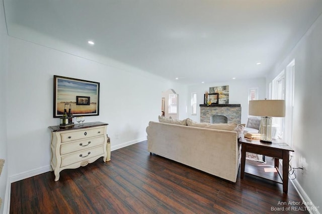 living room with dark hardwood / wood-style floors and a stone fireplace