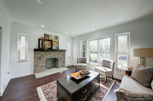 living room featuring a stone fireplace and dark hardwood / wood-style floors