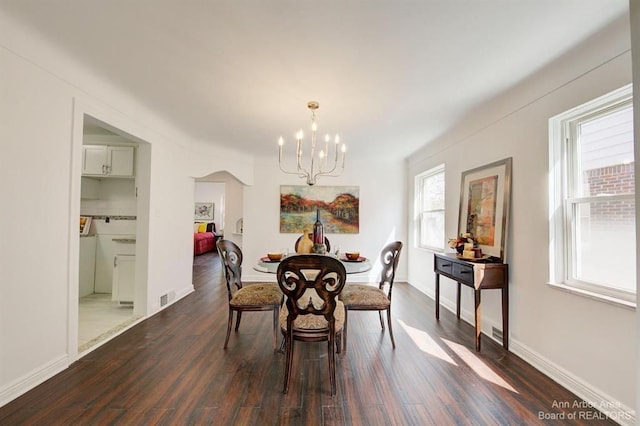 dining space with plenty of natural light, dark hardwood / wood-style flooring, and a chandelier