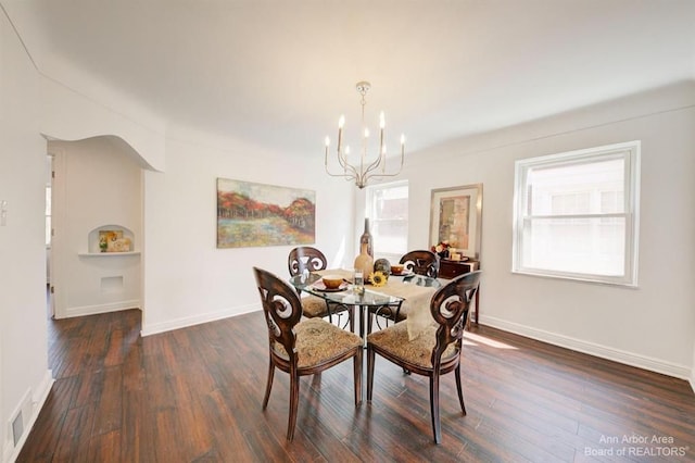 dining area with dark wood-type flooring and a chandelier