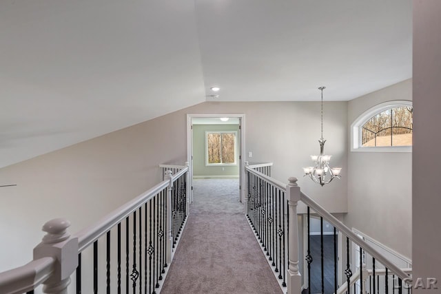 hallway with light carpet, a chandelier, and lofted ceiling