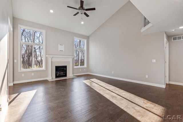 unfurnished living room with dark wood-type flooring, ceiling fan, a wealth of natural light, and high vaulted ceiling