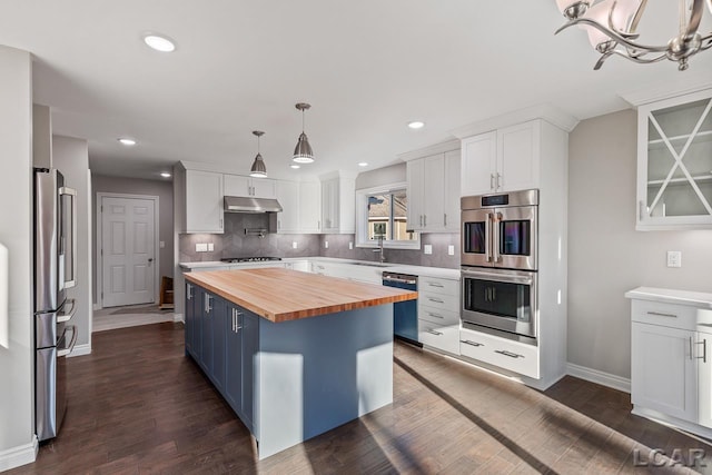 kitchen featuring butcher block countertops, white cabinets, a center island, and appliances with stainless steel finishes