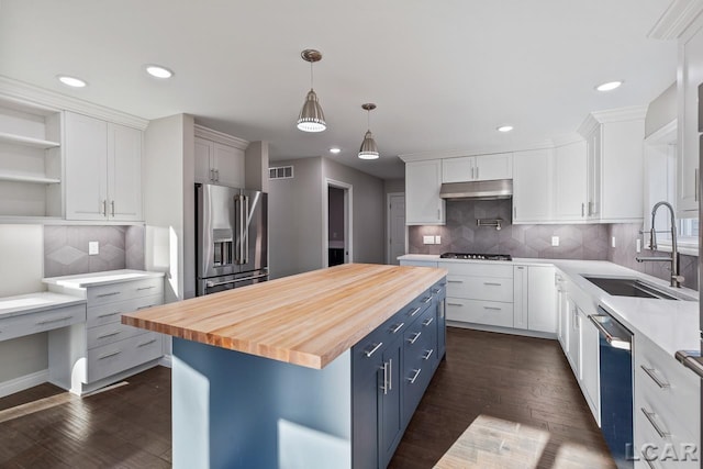 kitchen featuring wooden counters, appliances with stainless steel finishes, a kitchen island, white cabinets, and sink