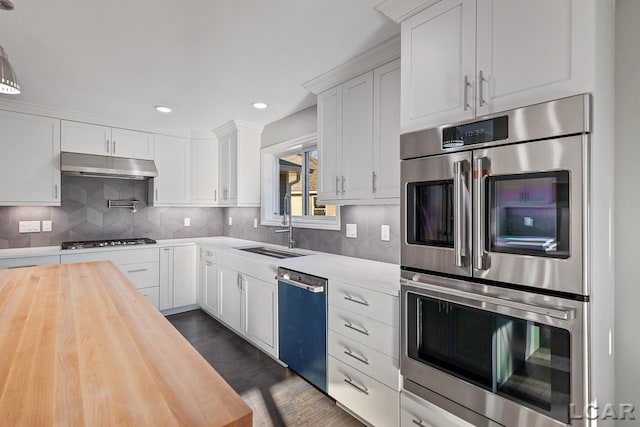 kitchen with dark wood-type flooring, white cabinetry, stainless steel appliances, sink, and butcher block countertops