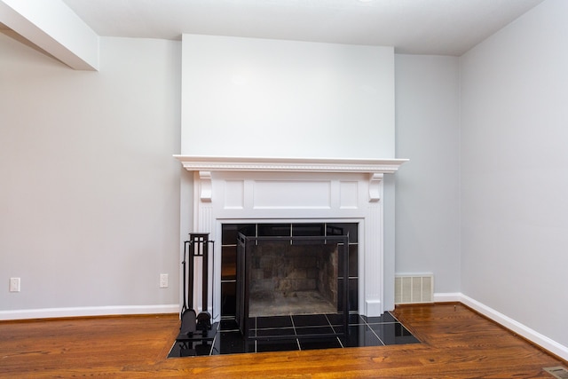 interior details featuring a tiled fireplace and hardwood / wood-style floors