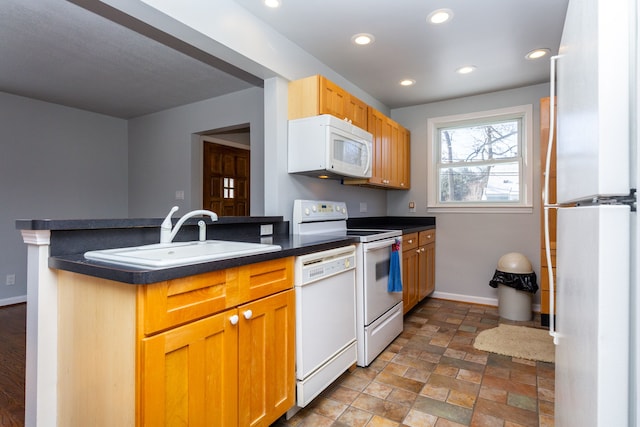 kitchen featuring kitchen peninsula, white appliances, and sink