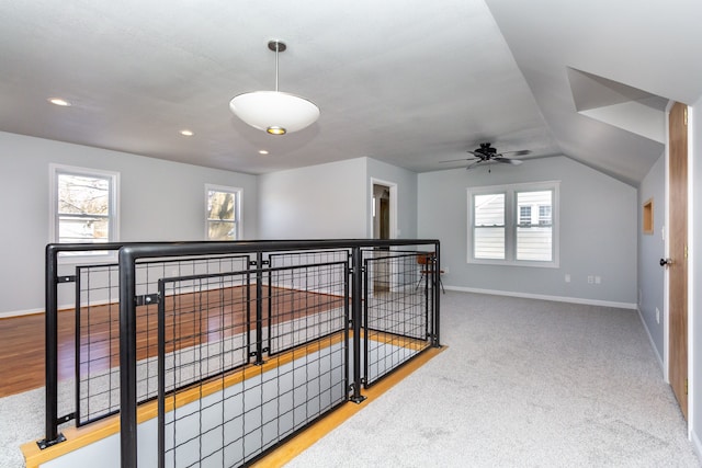 hall featuring light carpet, plenty of natural light, and vaulted ceiling