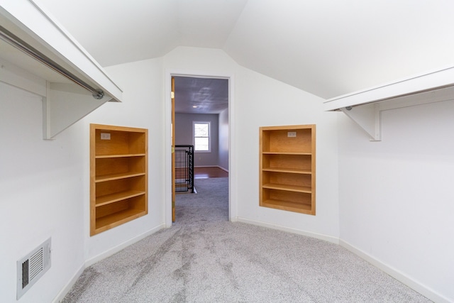 walk in closet featuring light colored carpet and lofted ceiling